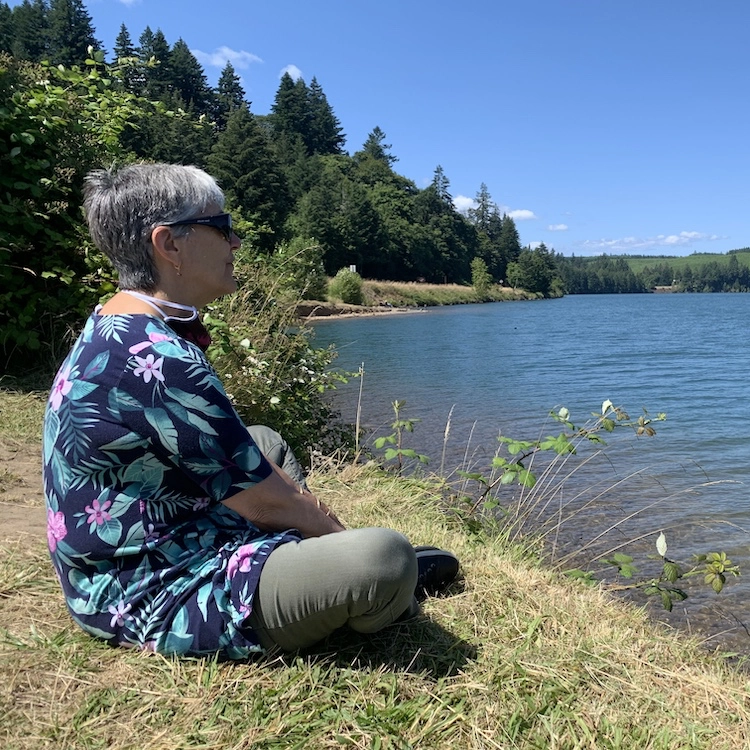 Pat sitting on grass by lake